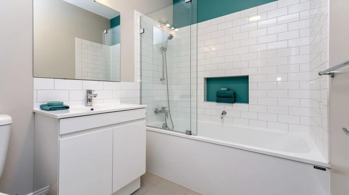 Compact renovated bathroom in an older Lower Hutt villa with a new vanity, subway tiles and a framed glass shower over the bath