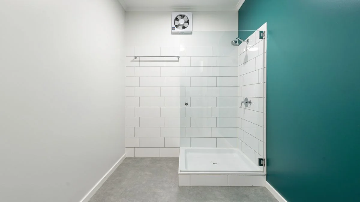 Renovated Palmerston North rental bathroom with a wall-mounted extractor fan above a tiled shower and a durable vinyl floor