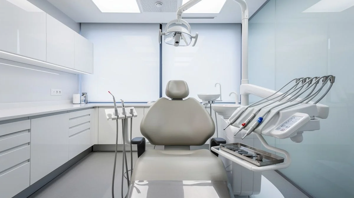 A clean modern dental surgery with a chair, overhead light and neatly organised instruments