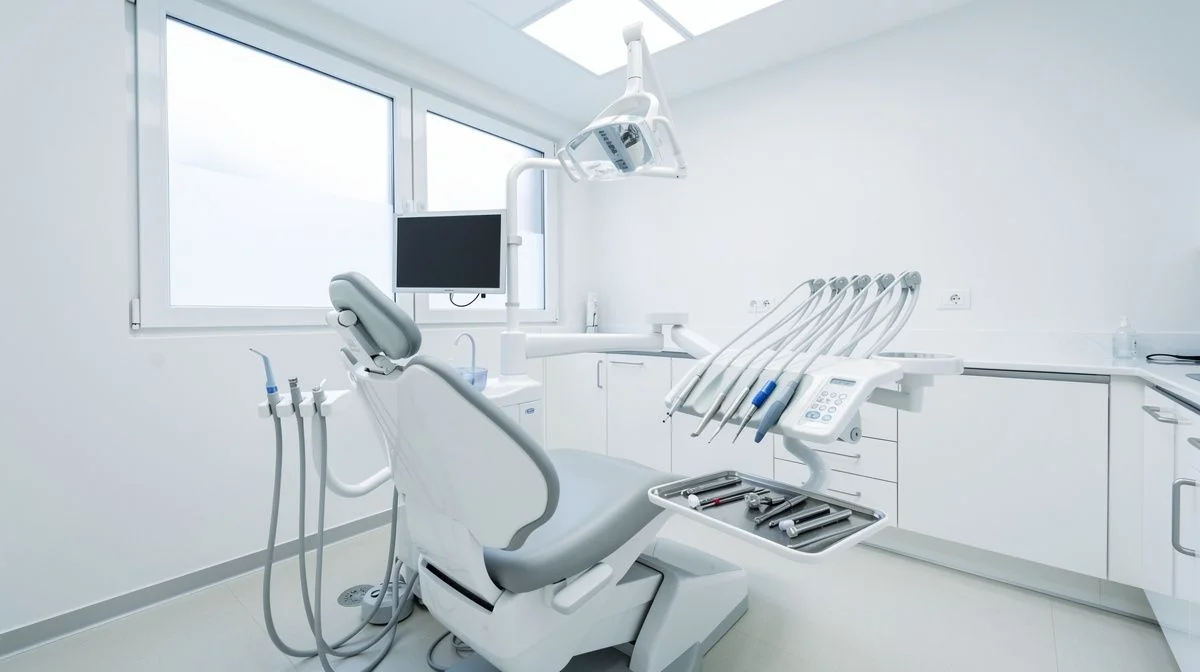 A clean modern dental surgery with a chair, overhead light and neatly organised instruments