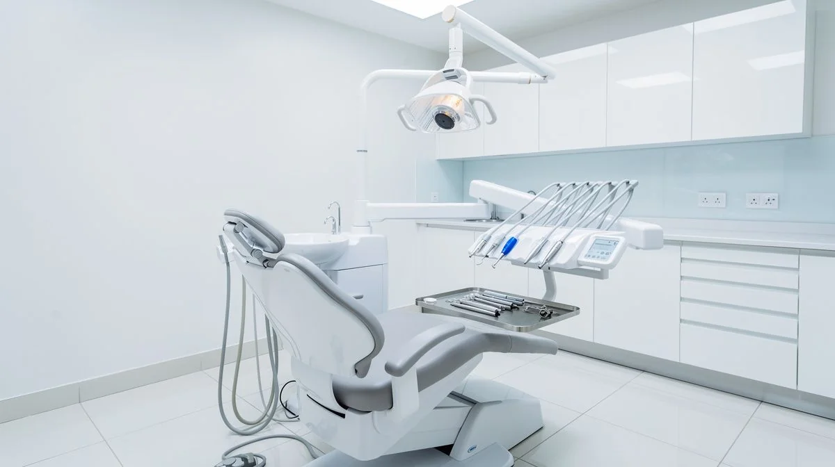 A clean modern dental surgery with a chair, overhead light and neatly organised instruments