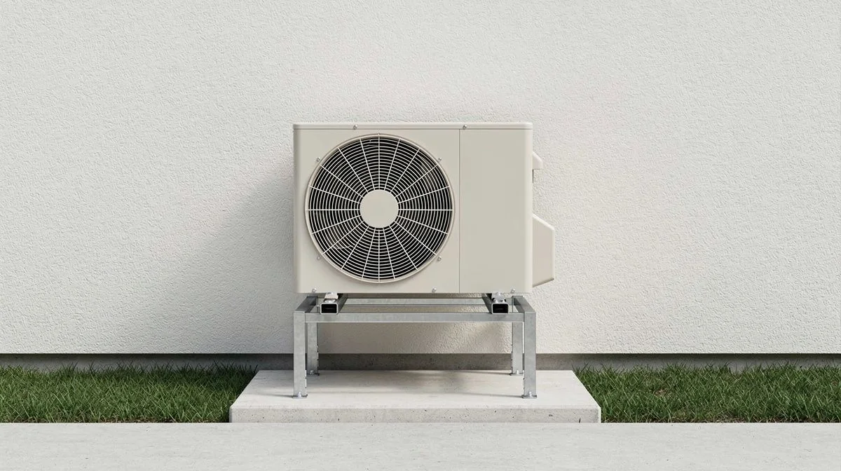 An outdoor heat pump unit mounted on a stand against the exterior wall of a home