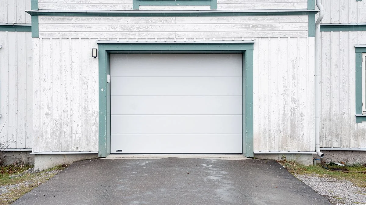 An insulated sectional garage door on an older Dunedin villa with a narrow driveway and a cold overcast sky