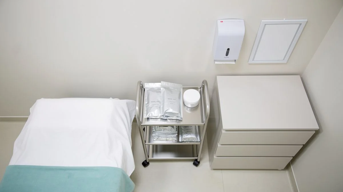 Clean beauty treatment room with covered bed and sterile tool trolley