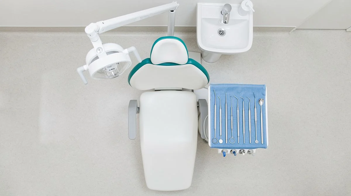 Dental examination room with chair, instrument tray and sink in daylight