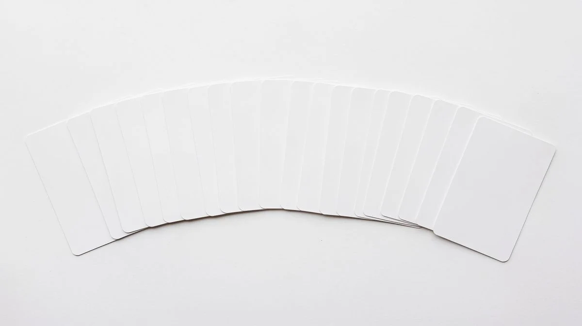 Blank plain white cards fanned out in a row on a bright white surface
