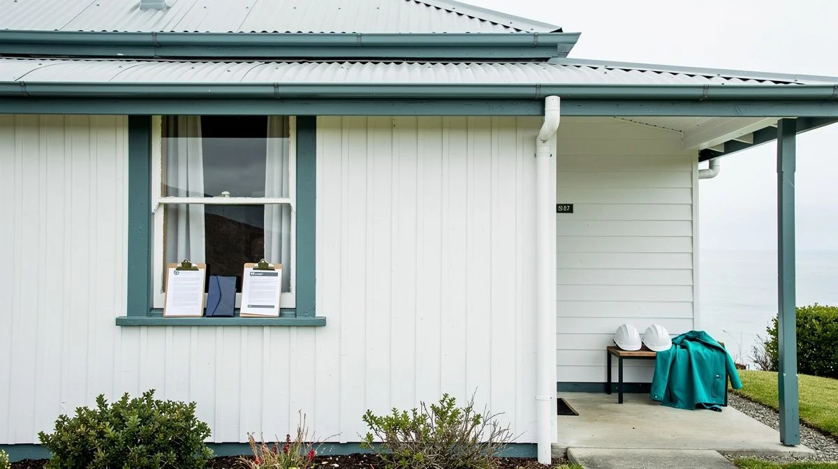 A broker inspecting weatherboard and roofing on an older Dunedin villa with the client