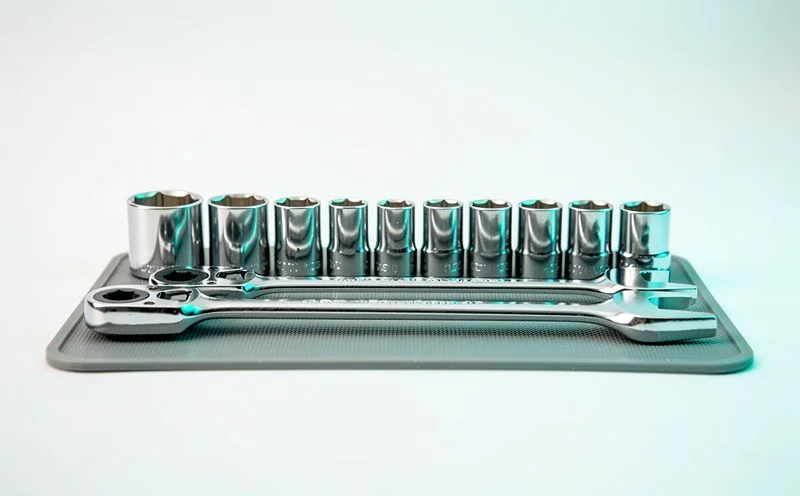 A chrome socket wrench set laid out in a neat row on a grey rubber mat